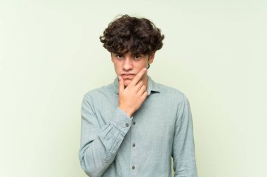 Izole yeşil duvar üzerinde genç adam bir fikir düşünme