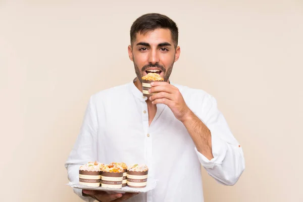 Schöner Mann mit Muffin-Kuchen über isoliertem Hintergrund — Stockfoto