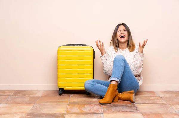 Traveler woman with suitcase sitting on the floor unhappy and frustrated with something