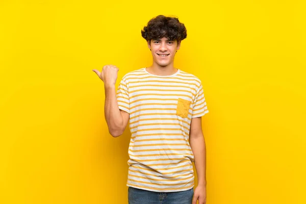 Junger Mann Über Isolierte Gelbe Wand Die Zur Seite Zeigt — Stockfoto