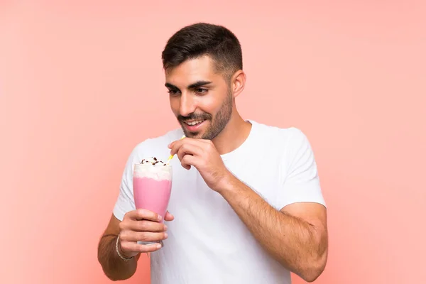 Joven con batido de fresa sobre fondo rosa aislado — Foto de Stock