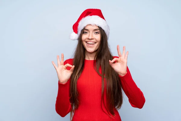 Meisje Met Kerst Hoed Geïsoleerde Blauwe Achtergrond Tonen Een Teken — Stockfoto