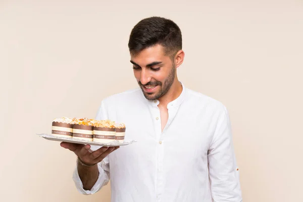 Handsome Man Holding Muffin Kaka Över Isolerade Bakgrund Leende Mycket — Stockfoto