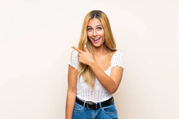 Junge Blonde Frau Über Isolierten Hintergrund Zeigt Mit Dem Finger — Stockfoto