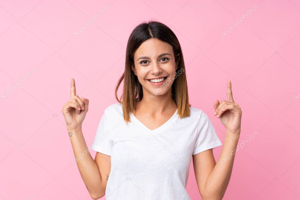 Young woman over isolated pink background pointing up a great idea