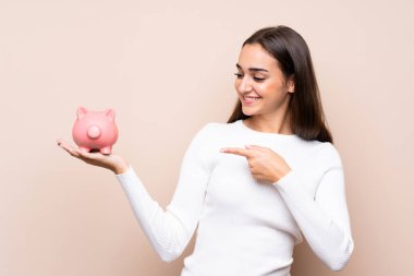 Tecrit edilmiş genç bir kadın elinde büyük bir kumbara tutuyor.