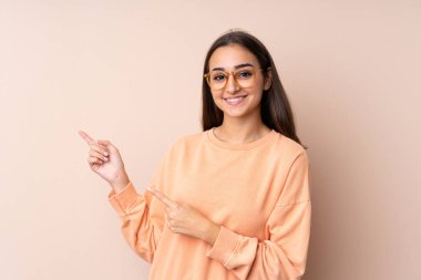 İzole edilmiş arka planda genç bir kız parmağı yana işaret ediyor.
