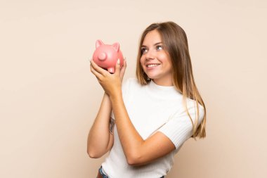 Tecrit edilmiş genç sarışın kadın elinde büyük bir kumbara tutuyor.