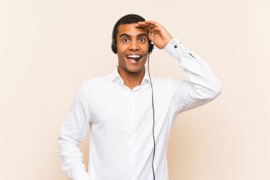 Genç esmer adam, şaşırmış ve şok olmuş yüz ifadesi olan bir kulaklıkla çalışıyor.