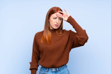 Genç kızıl saçlı kadın soyutlanmış mavi arka planda yorgun ve hasta bir ifadeyle