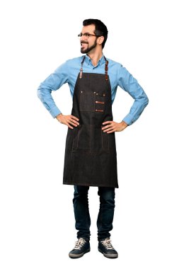 Kolları kalçasında poz veren ve izole edilmiş beyaz arka planda gülümseyen önlüklü bir adamın tam boy resmi.