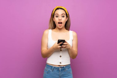 İzole mor duvar üzerinde Pretty genç kadın sürpriz ve bir mesaj gönderme