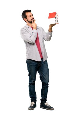 İzole beyaz arka plan üzerinde küçük bir ev tutarak sakallı yakışıklı adam tam uzunlukta atış