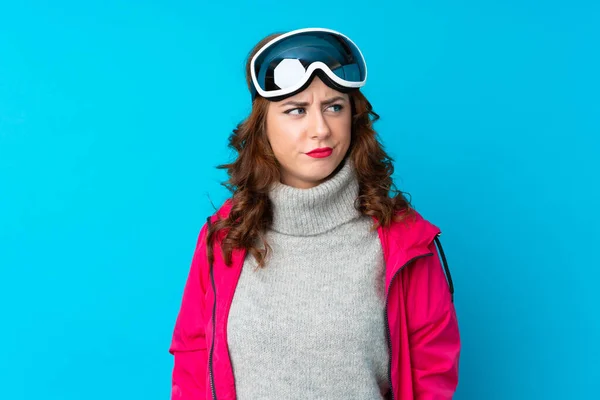 Narciarka Okularami Snowboardowymi Odizolowanej Niebieskiej Ścianie Stojącej Spoglądającej Bok — Zdjęcie stockowe