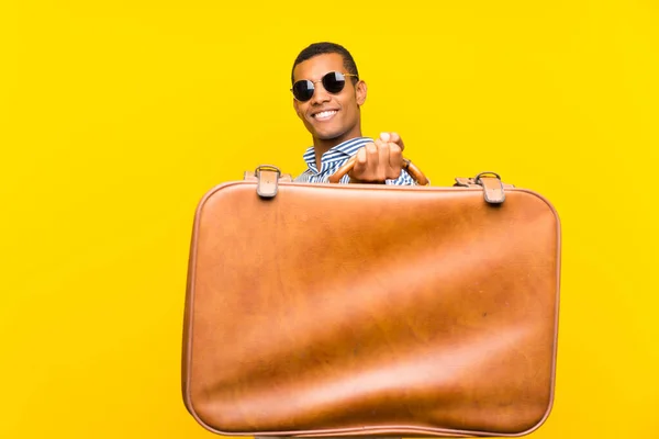 Hombre morena sosteniendo un maletín vintage sobre fondo amarillo aislado —  Fotos de Stock