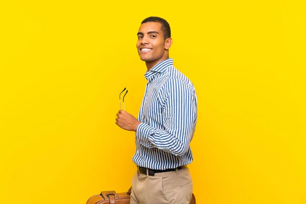 Брюнетка чоловік тримає Vintage портфель на ізольований жовтий фон — стокове фото