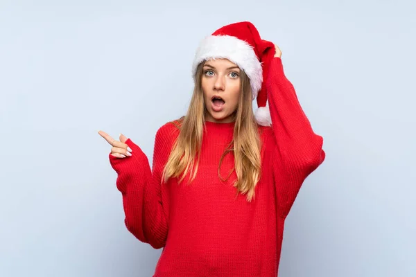 Chica Con Sombrero Navidad Sobre Fondo Azul Aislado Sorprendido Señalando — Foto de Stock