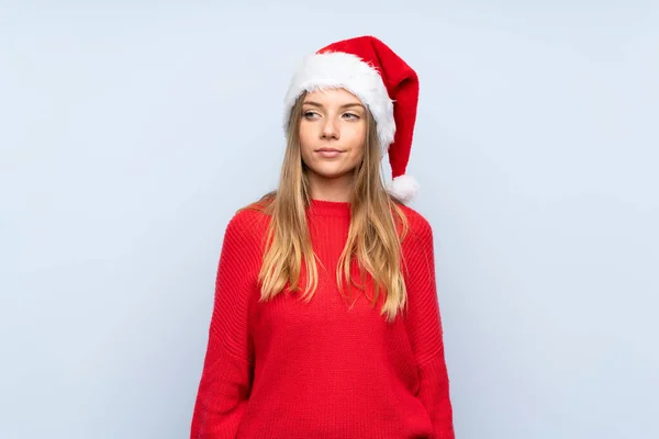 Meisje Met Kerst Hoed Geïsoleerde Blauwe Achtergrond Staan Kijken Naar — Stockfoto