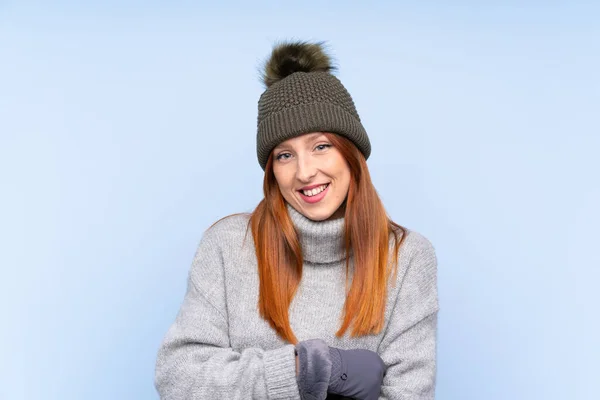 若いですRedheadロシア人女性とともに冬の帽子以上隔離された青の背景笑い — ストック写真