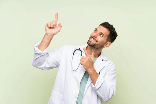 Junger Arzt Zeigt Mit Dem Zeigefinger Auf Grüne Wand — Stockfoto