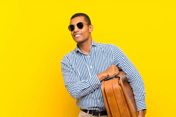 Bruna uomo in possesso di una valigetta vintage su isolato sfondo giallo — Foto Stock