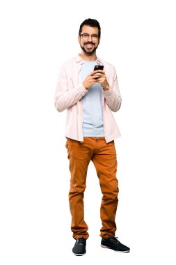 İzole beyaz arka plan üzerinde mobil ileti gönderme sakallı yakışıklı adam tam uzunlukta atış