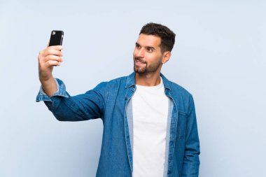 Izole mavi arka plan üzerinde yakışıklı adam selfie yapma