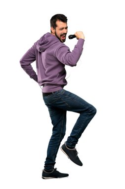 Tişörtlü yakışıklı adam mikrofonla şarkı söylüyor.