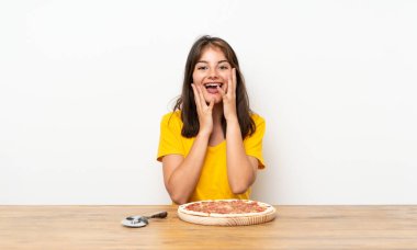 Suratı şaşkın bir şekilde pizza yiyen beyaz kız.
