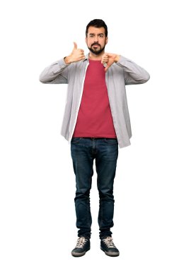 Tam uzunlukta bir kadeh iyi-kötü işaret yapma sakallı yakışıklı adam. Kararsız Evet arasında veya izole beyaz arka plan üzerinde değilken