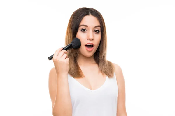 Mladá žena přes izolované bílé pozadí s make-up kartáč — Stock fotografie