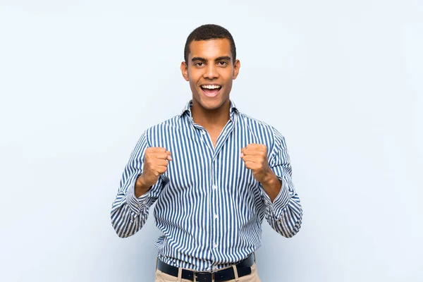 Genç Yakışıklı Esmer Adam Mavi Arka Planda Zaferi Kutluyor — Stok fotoğraf