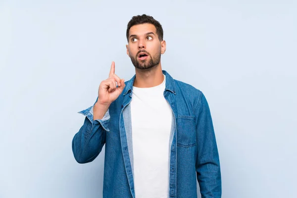 Hombre Guapo Sobre Fondo Azul Aislado Pensando Una Idea Apuntando — Foto de Stock