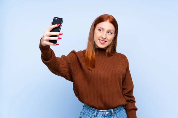 Joven Pelirroja Sobre Fondo Azul Aislado Haciendo Una Selfie —  Fotos de Stock
