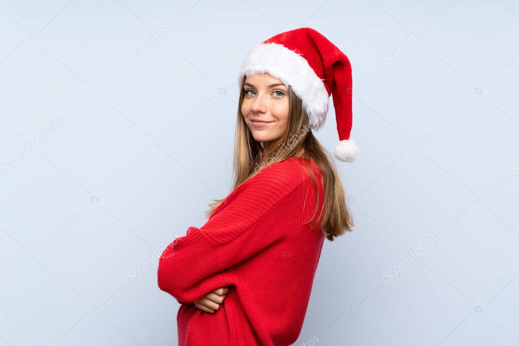Girl with christmas hat over isolated blue background laughing