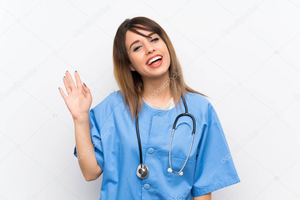 Young nurse woman over white wall saluting with hand with happy expression