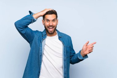 Izole mavi arka plan üzerinde Yakışıklı adam şaşırttı ve yan parmak işaret