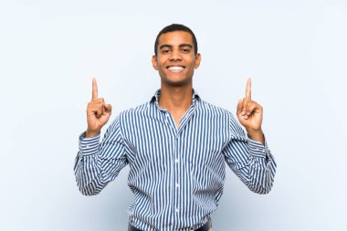 Genç, yakışıklı, esmer, soyutlanmış mavi arka planlı adam harika bir fikre işaret ediyor.