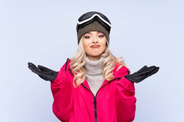 Kayakçı kız, kayak gözlüklü, mavi arka planda, kafası karışık bir yüz ifadesine sahip.