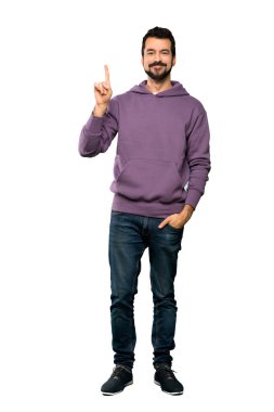 Sweatshirt 'lü yakışıklı bir adamın, izole edilmiş beyaz arka planda en iyi görüntünün işareti olarak parmağını kaldırması.