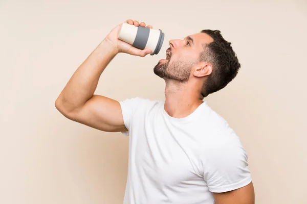 Bonito homem sobre fundo isolado segurando um café take away — Fotografia de Stock