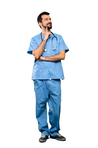 孤立した白い背景を見上げながらアイデアを考えている外科医の男の完全長ショット — ストック写真