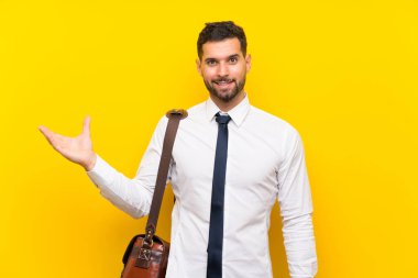 Sarı arka plan üzerinde yakışıklı bir iş adamı. Avucunun içinde sanal bir telif alanı tutuyor.