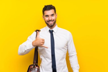 Yakışıklı iş adamı izole edilmiş sarı arka planda telefon jesti yapıyor.