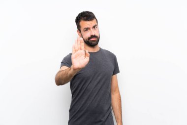 Soyutlanmış beyaz arka planda genç yakışıklı adam dur hareketi yapıyor.