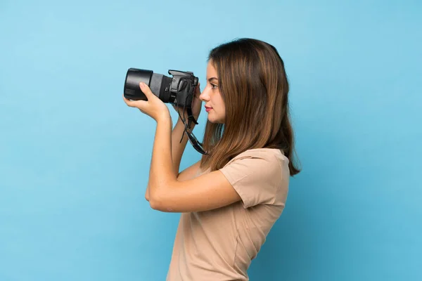 Молода Брюнетка Над Ізольованим Синім Тлом Професійною Камерою — стокове фото