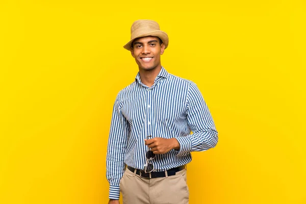 Morena homem segurando uma pasta vintage sobre fundo amarelo isolado — Fotografia de Stock