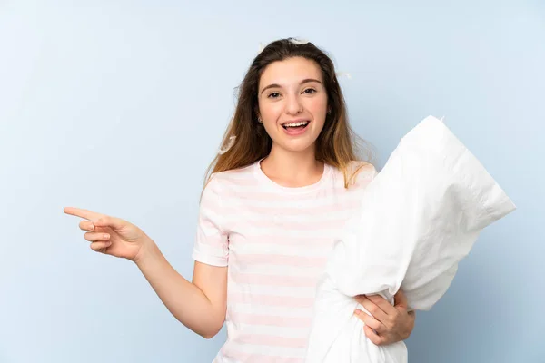 Mujer Joven Pijama Sobre Fondo Azul Aislado Sorprendida Señalando Con — Foto de Stock