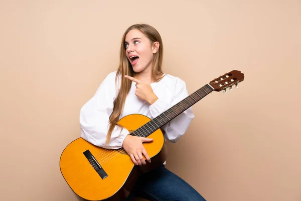 Tiener Meisje Met Gitaar Geïsoleerde Achtergrond Verrast Wijzend Kant — Stockfoto