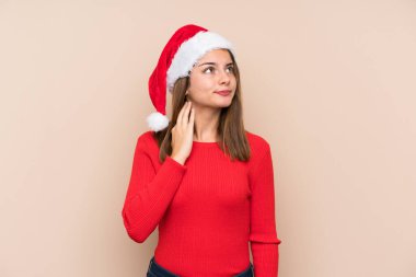Yılbaşı şapkası takmış genç bir kız izole bir arka plan düşünüyor.